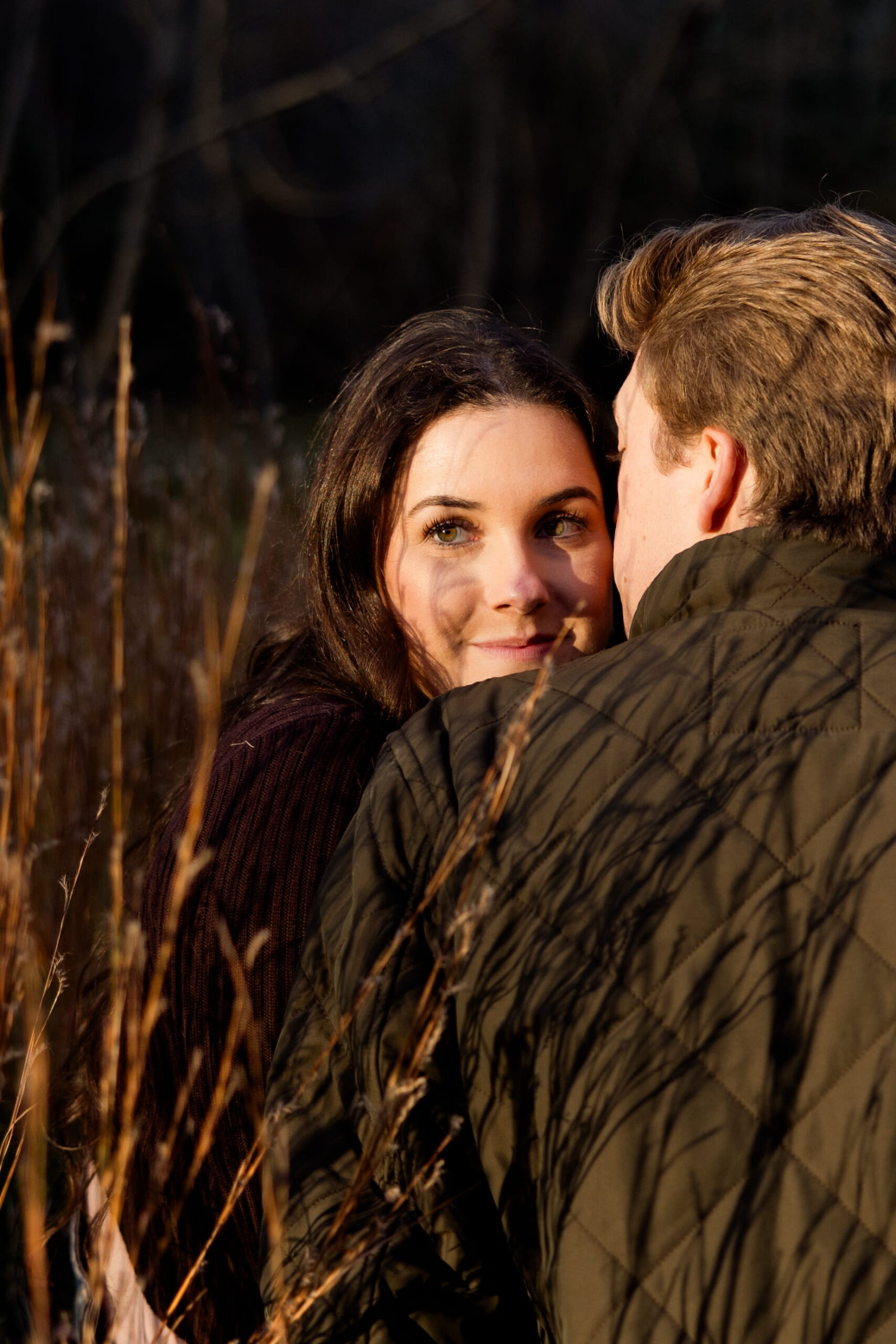 Man and woman kiss in a field during their engagement session in New England.