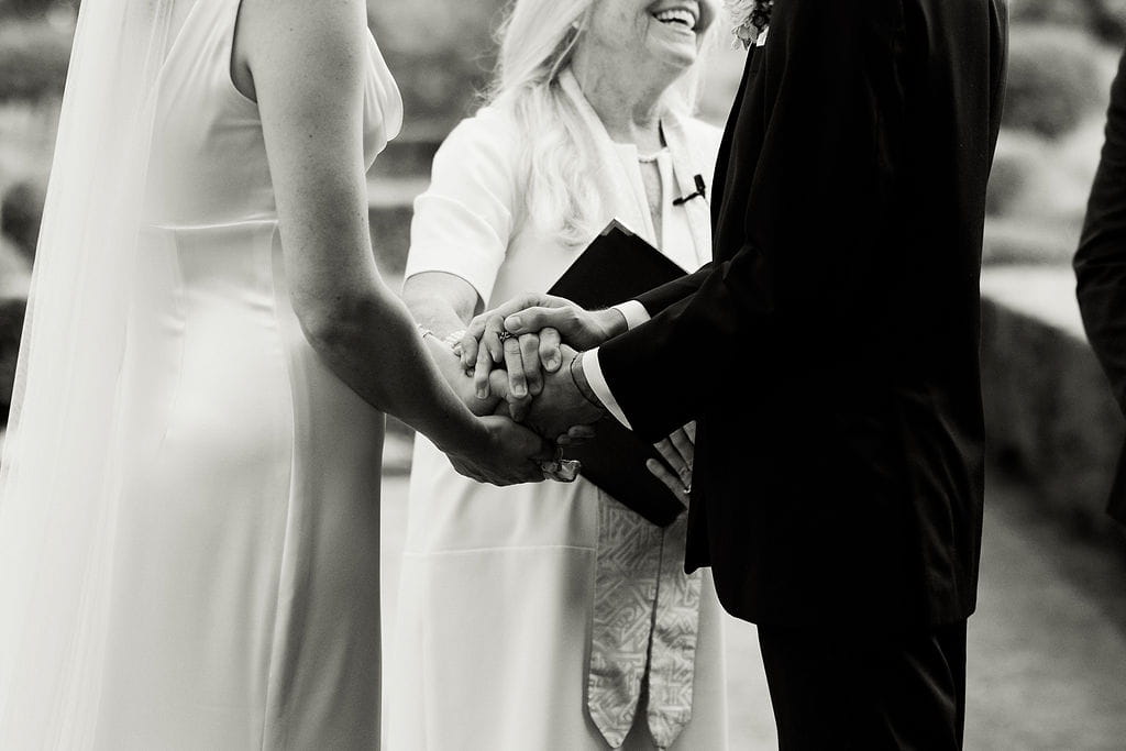 New England wedding officiant holds the couples hands during their intimate wedding ceremony. 