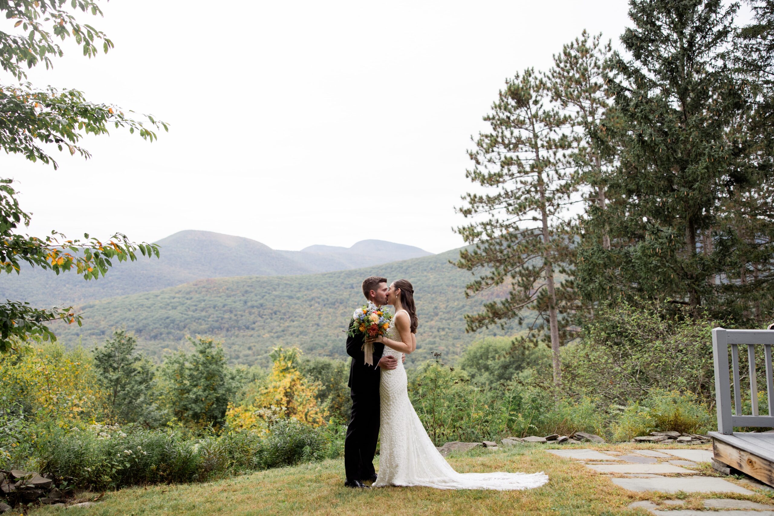 Bride and groom kiss on the lawn of their Catskill Mountains wedding venue in New York. 