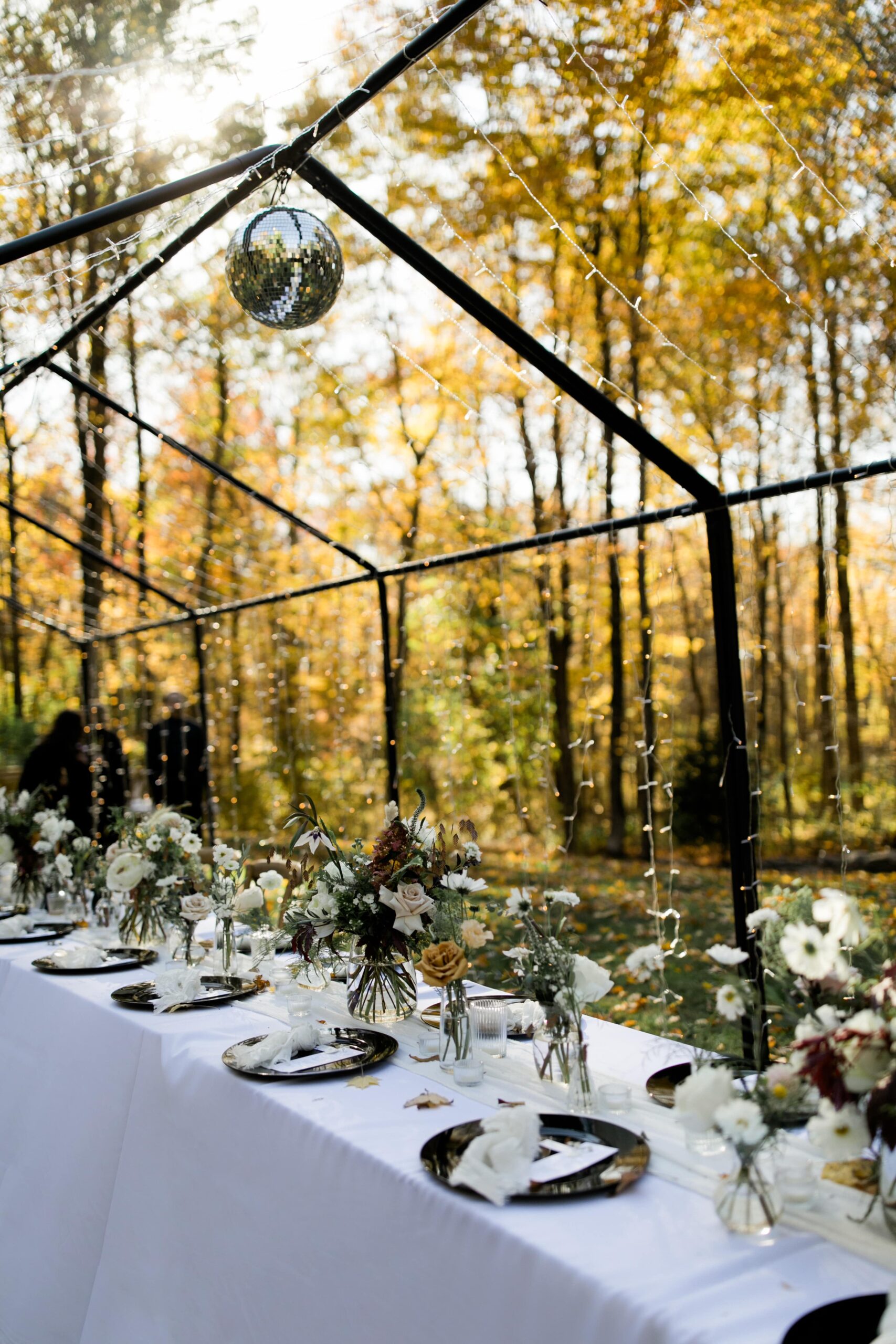 Black and white outdoor wedding reception dinner with fall colors and floral decorations.