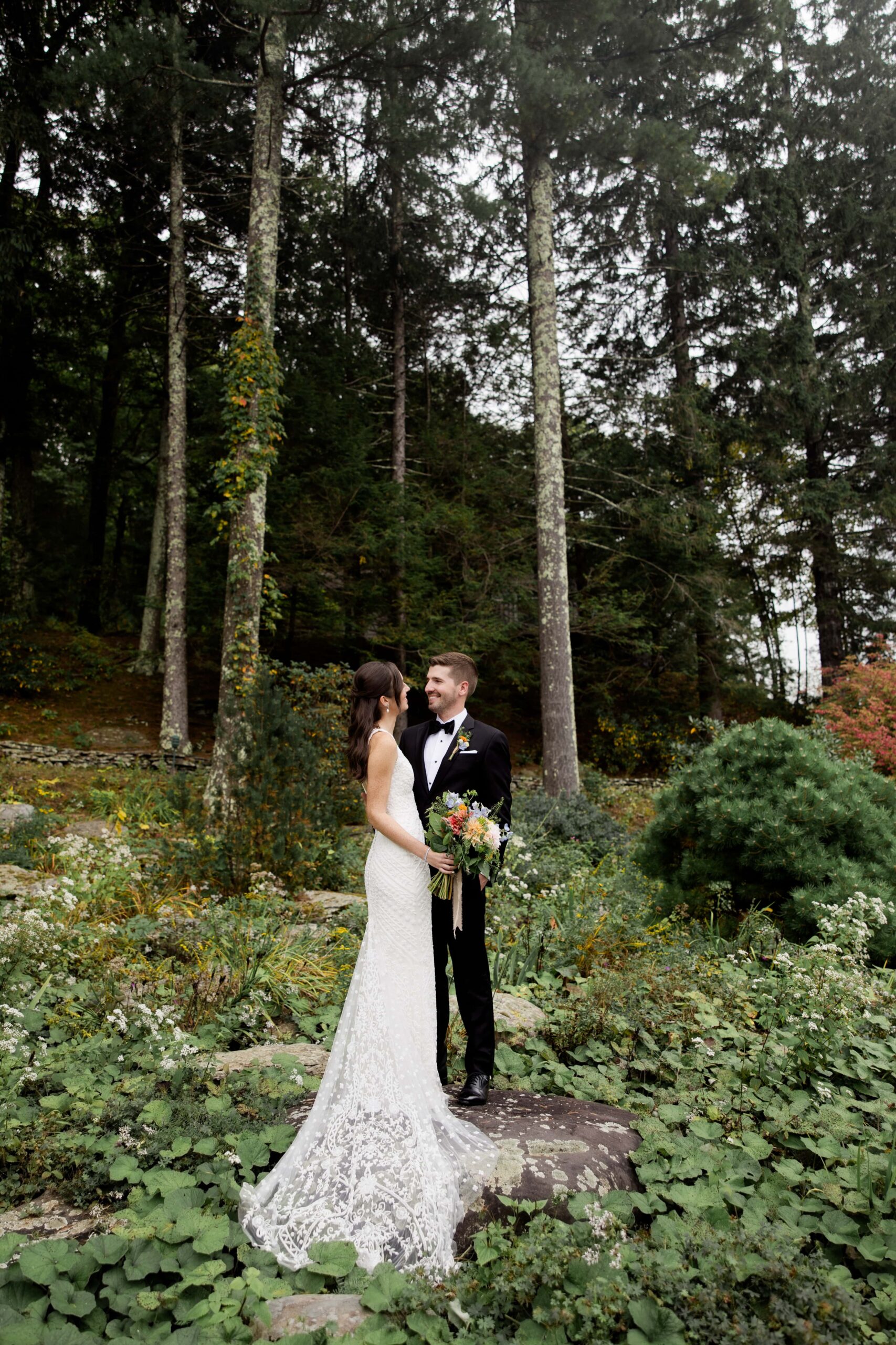 Bride and groom stand in a green forest during their Upstate New York elopement. 