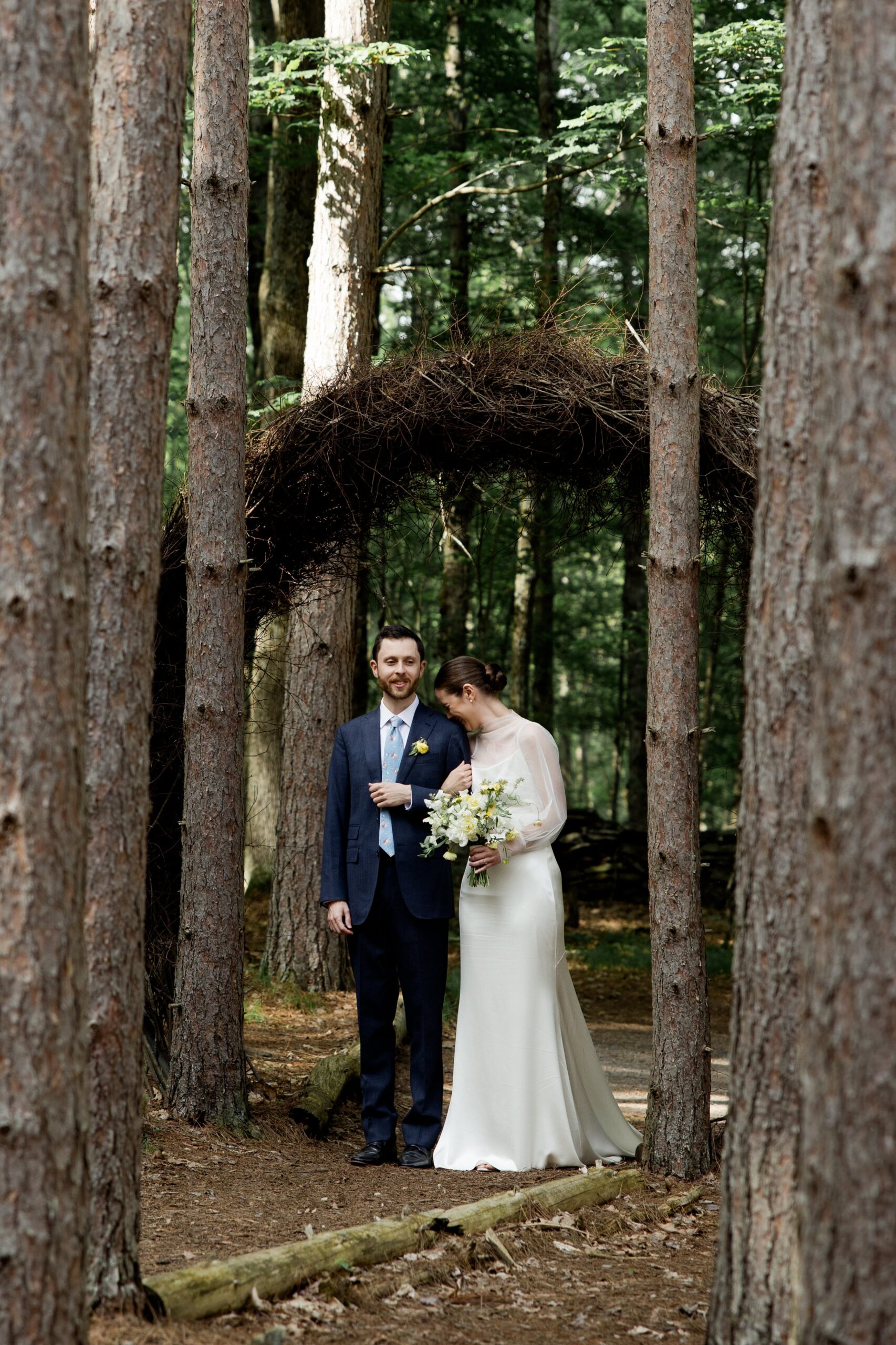 Bride rests her head against groom's shoulder while walking through the forest during their Roxbury Barn & Estate wedding. 