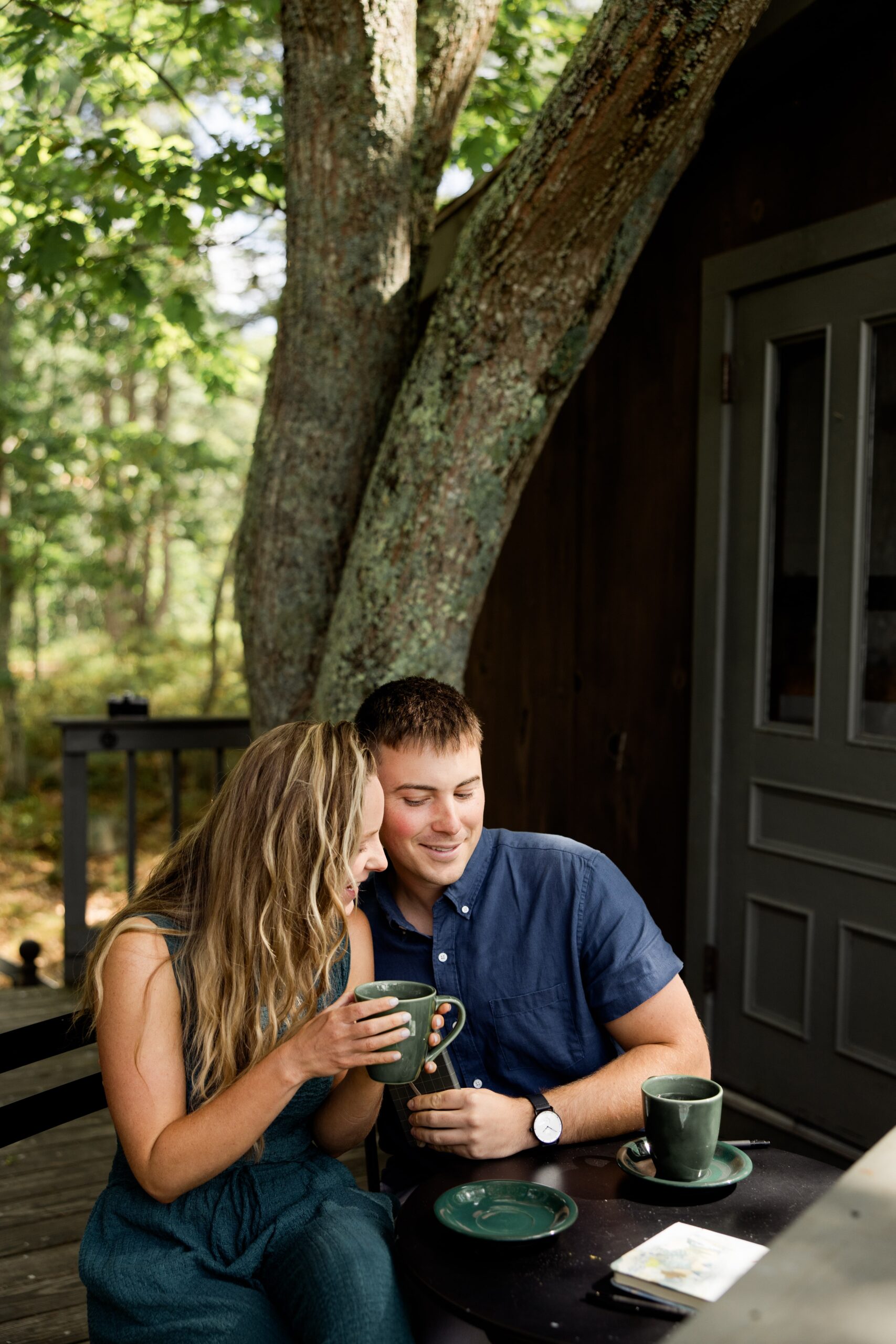 Couple drinks coffee on the patio of their treehouse cabin in Maine. 