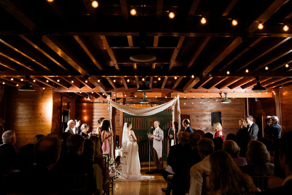 Bride and groom stand at an indoor wedding altar exchanging vows during their documentary style wedding.
