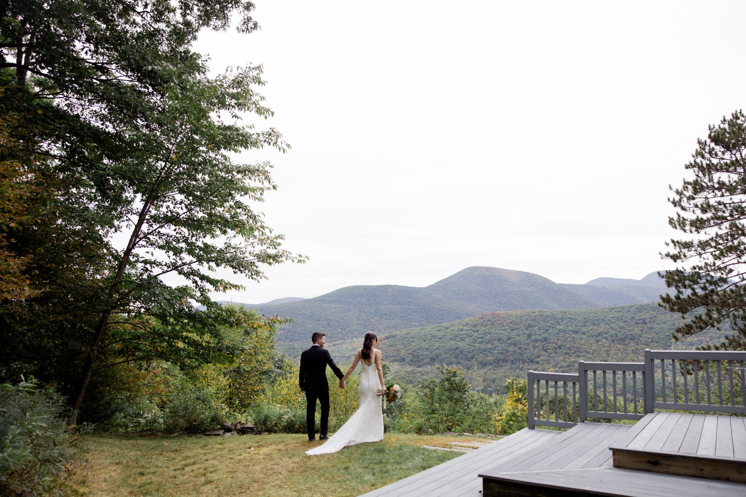 Bride and groom hold hands while lookout out over a mountain valley during their elopement in Upstate NY. 
