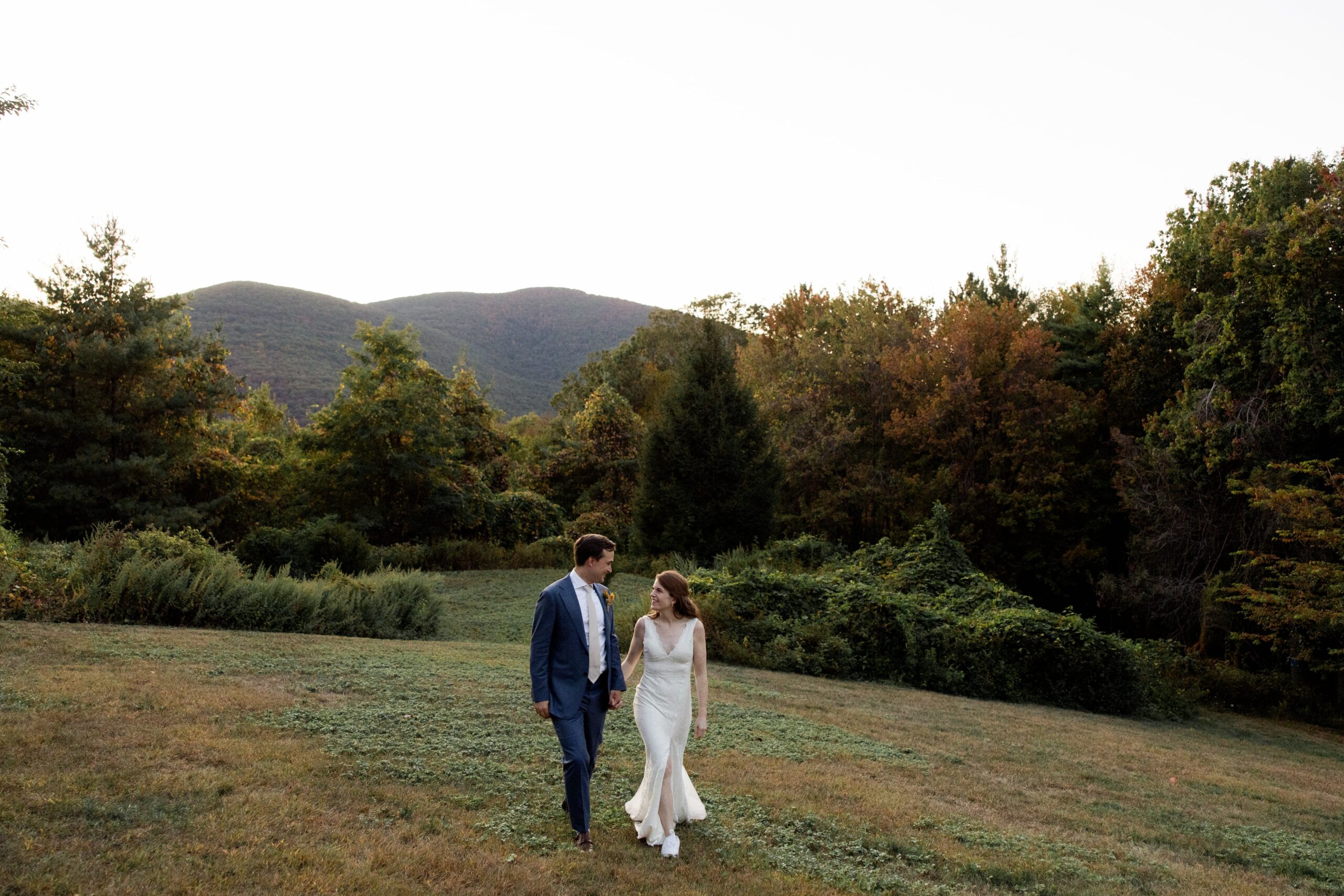 Bride and groom hold hands while walking through nature during their elopement in Upstate New York.