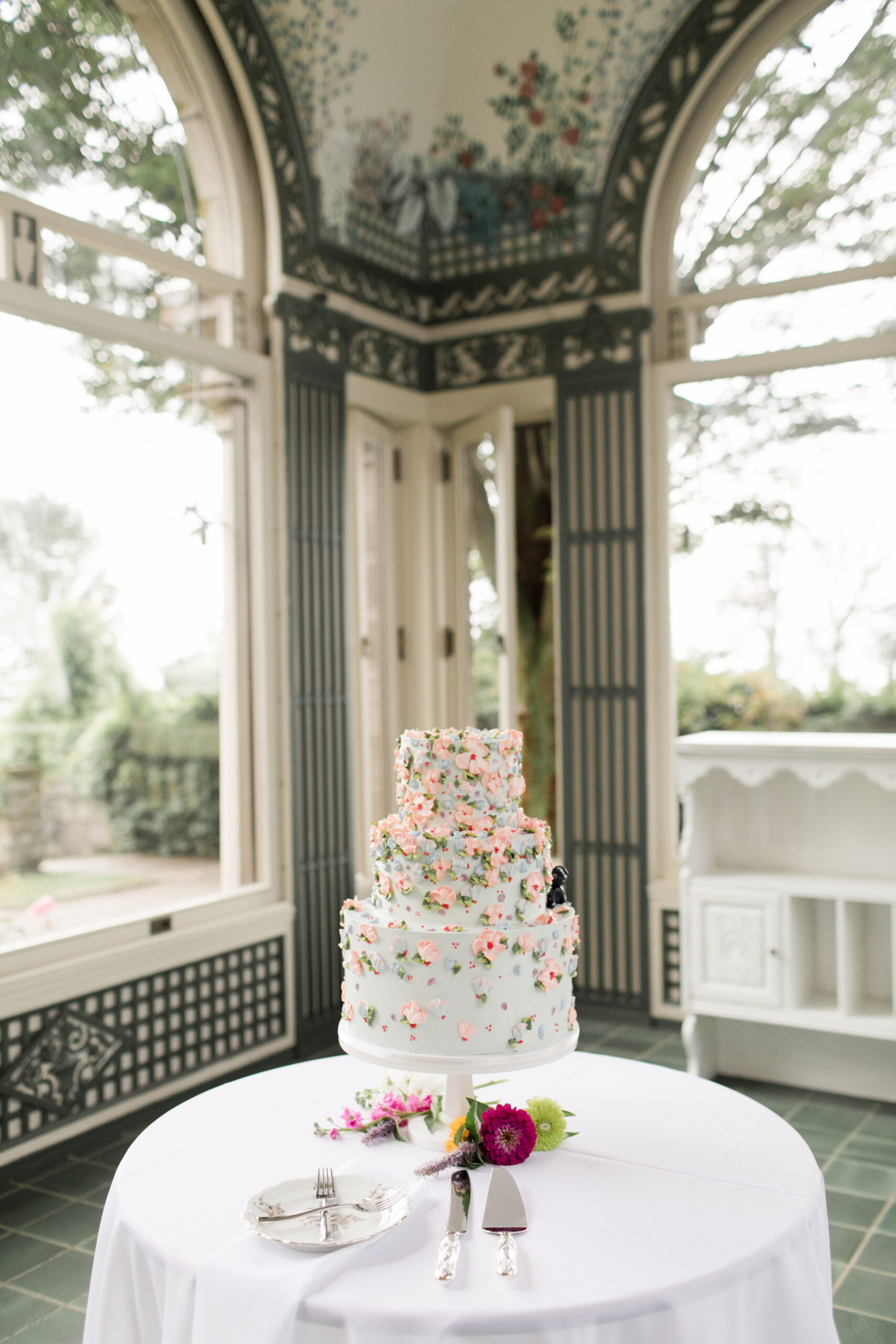 Three tier wedding cake with pink flowers in a covered terrace at Eolia Mansion.