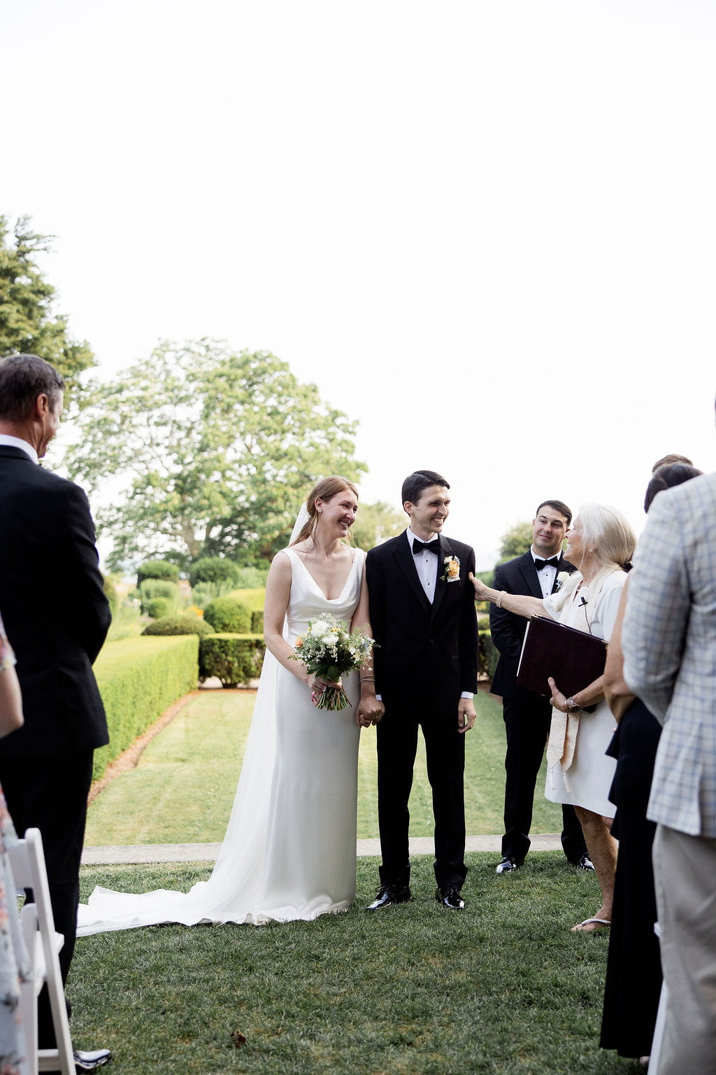 Officiant speaks to smiling newlyweds during their wedding ceremony in New England. 